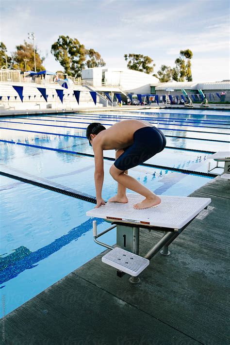 Row of naked boys stand on diving board at indoor pool